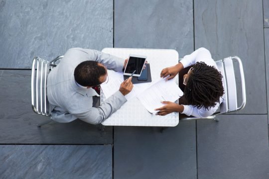 African American man pointing on tablet African American man pointing on tablet. Top view of two business people looking at tablet. Business meeting concept